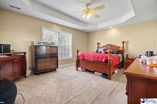 carpeted bedroom featuring ceiling fan and a raised ceiling