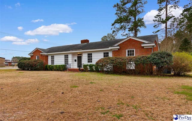 ranch-style house with brick siding, a chimney, and a front lawn