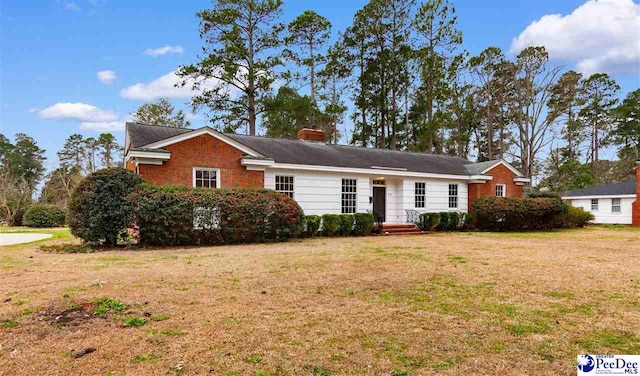 ranch-style home with a front yard, brick siding, and a chimney