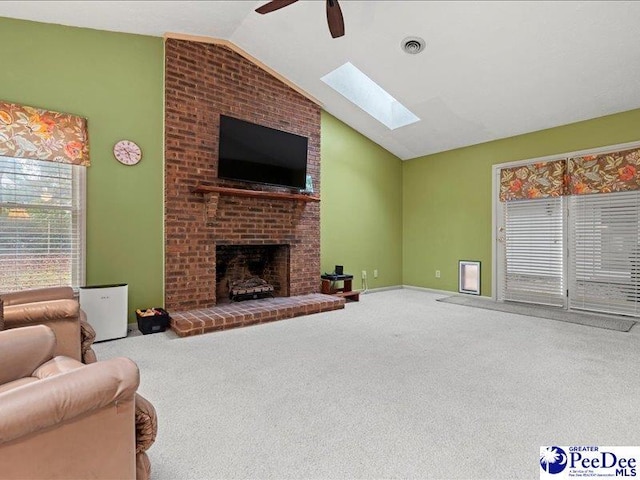 living room featuring ceiling fan, carpet flooring, vaulted ceiling with skylight, and a fireplace