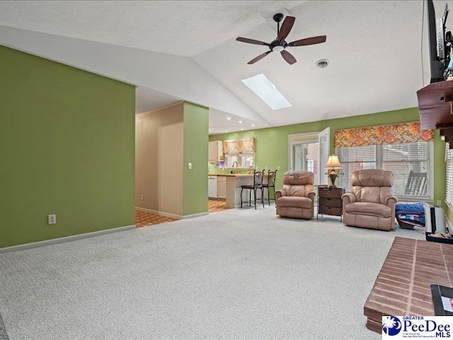 carpeted living room with ceiling fan, high vaulted ceiling, a textured ceiling, and a skylight