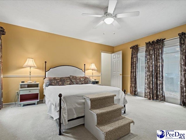 bedroom with ceiling fan, light colored carpet, and a textured ceiling