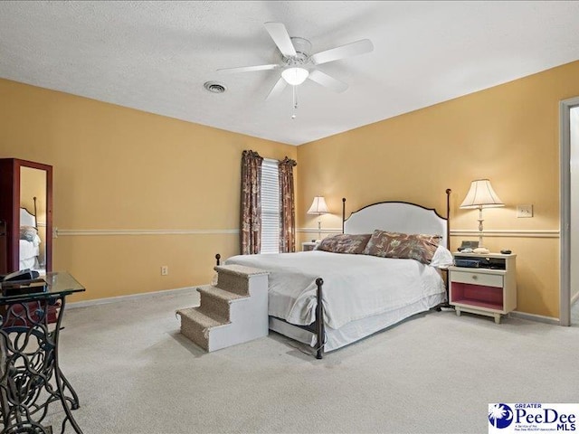 carpeted bedroom featuring ceiling fan and a textured ceiling