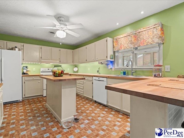 kitchen with wood counters, sink, a center island, ceiling fan, and white appliances