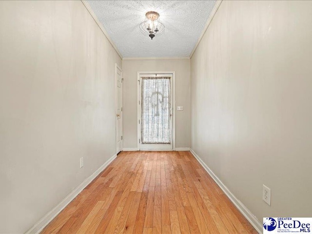 doorway featuring crown molding, a textured ceiling, and light wood-type flooring