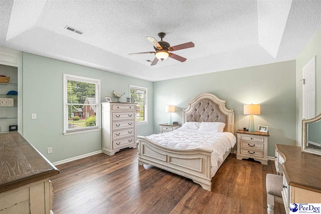 912 Ivanhoe Dr, Florence, SC 29505 - bedroom with a textured ceiling, dark wood-style flooring, a raised ceiling, and a ceiling fan