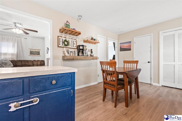 dining room with light wood-style flooring, baseboards, and ceiling fan