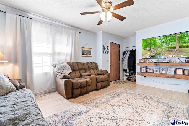 living room featuring a textured ceiling, ceiling fan, wood finished floors, and crown molding