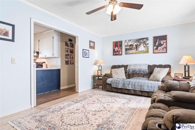 living room with ornamental molding, light wood-style flooring, a textured ceiling, and a ceiling fan