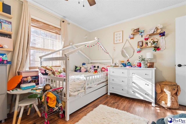 bedroom featuring a textured ceiling, ceiling fan, ornamental molding, and wood finished floors