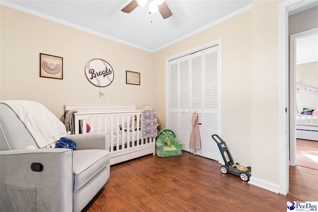 bedroom with a closet, ornamental molding, ceiling fan, wood finished floors, and baseboards