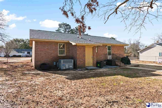 rear view of house featuring cooling unit and brick siding