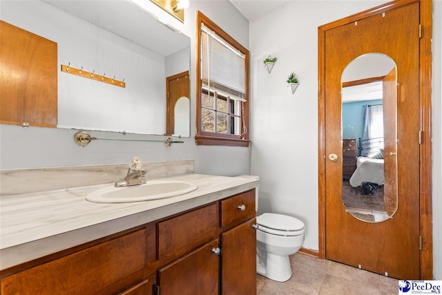 bathroom with toilet, vanity, and tile patterned floors