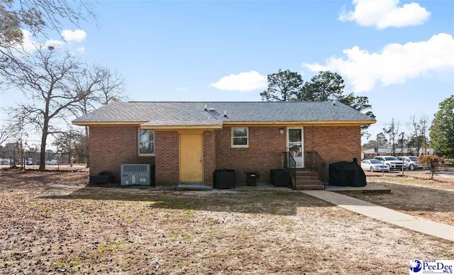 rear view of property featuring entry steps, brick siding, and cooling unit