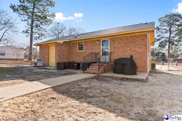 rear view of property featuring fence and brick siding