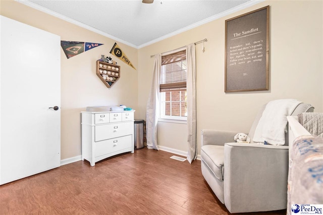 sitting room with visible vents, crown molding, baseboards, and wood finished floors