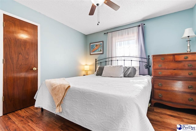 bedroom with ceiling fan, a textured ceiling, and wood finished floors