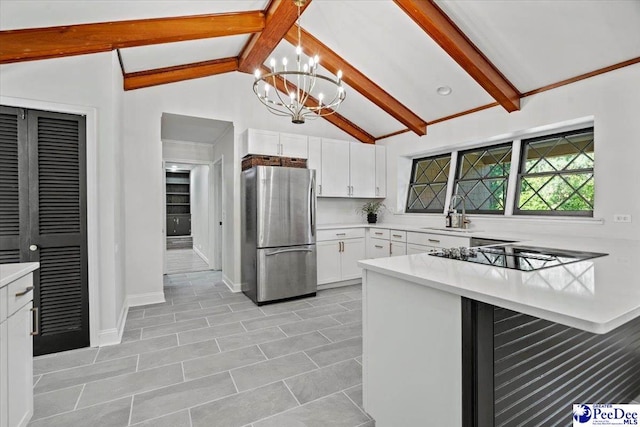 kitchen with sink, white cabinetry, a chandelier, black electric cooktop, and stainless steel fridge