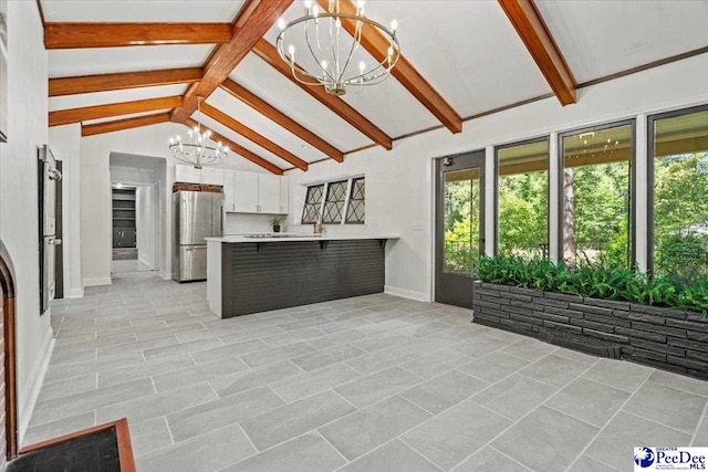 unfurnished living room featuring an inviting chandelier, beam ceiling, and high vaulted ceiling