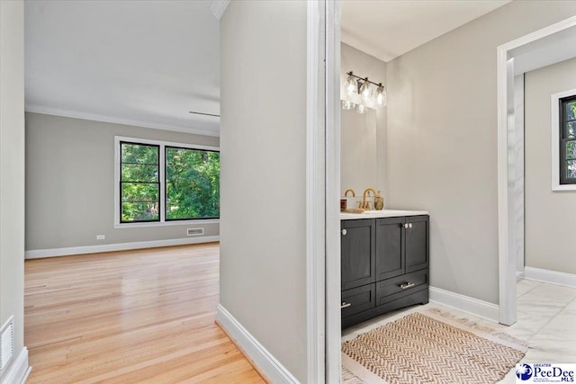 bathroom with hardwood / wood-style flooring, vanity, a healthy amount of sunlight, and ornamental molding