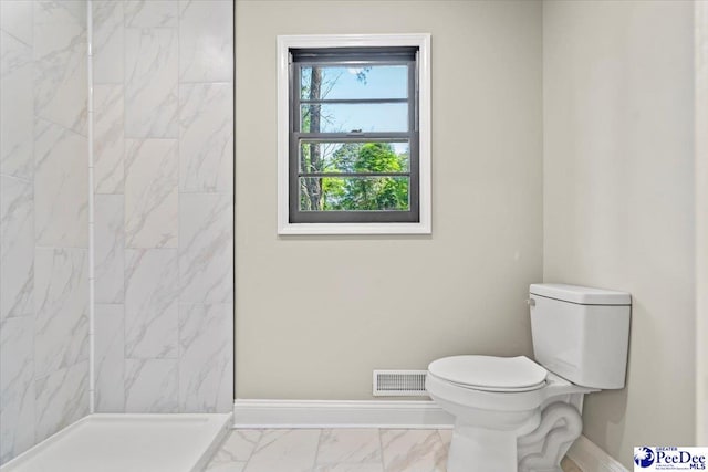 bathroom with tiled shower and toilet