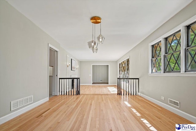 spare room with an inviting chandelier and light wood-type flooring