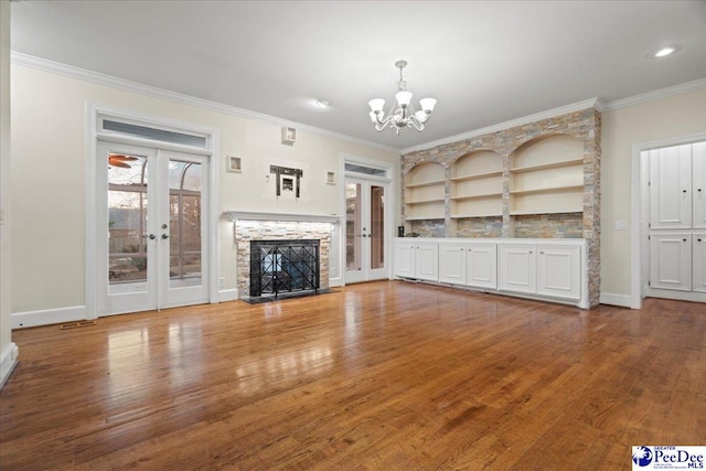 3406 Sussex Ct, Florence, SC 29501 - unfurnished living room featuring french doors, a stone fireplace, a chandelier, light wood-type flooring, and ornamental molding