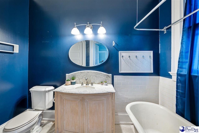 bathroom featuring vanity, toilet, a bathtub, and tile walls