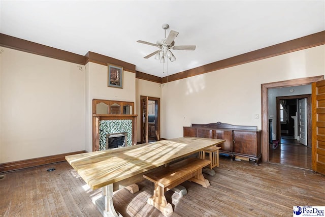 dining space with dark wood-type flooring, a fireplace, and ceiling fan