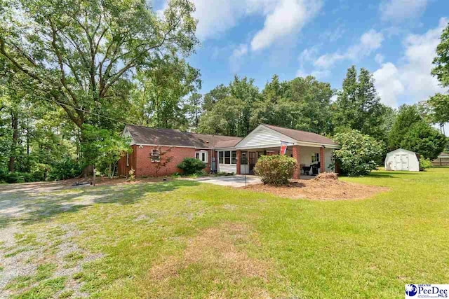 23 Mcrae Rd, Cheraw, SC 29520 - back of property featuring a storage shed, a yard, brick siding, and an attached carport