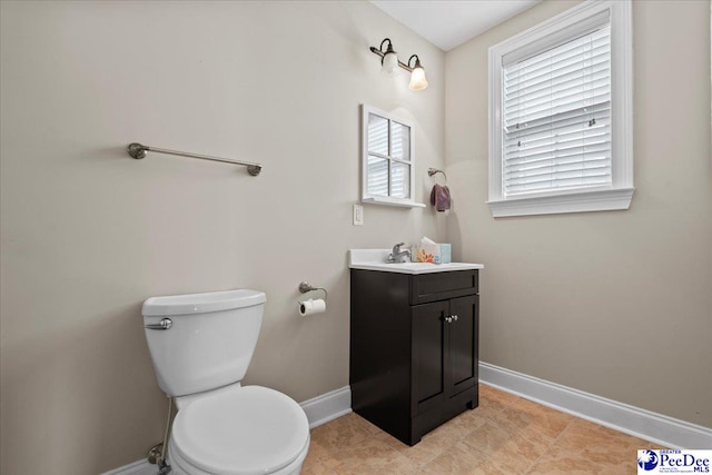 bathroom with toilet, vanity, and baseboards