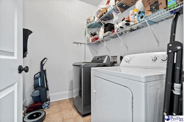 washroom with light tile patterned floors, baseboards, separate washer and dryer, and laundry area