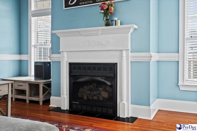 room details with a fireplace with flush hearth, wood finished floors, and baseboards