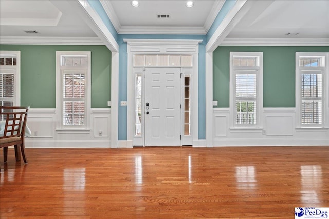 foyer entrance featuring visible vents, crown molding, and wood finished floors