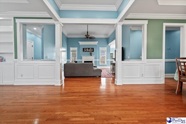 entryway featuring a decorative wall, a fireplace, crown molding, and wood finished floors