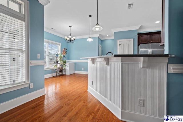 kitchen featuring baseboards, pendant lighting, a kitchen breakfast bar, wood finished floors, and stainless steel fridge