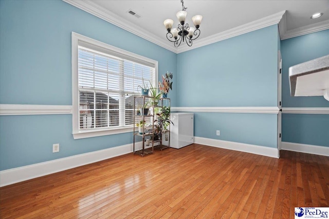 unfurnished room featuring a chandelier, visible vents, crown molding, and hardwood / wood-style floors