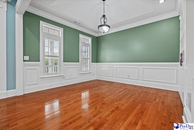 unfurnished dining area with hardwood / wood-style flooring, crown molding, and a wainscoted wall