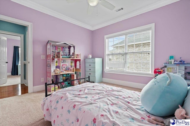 carpeted bedroom with a ceiling fan, visible vents, baseboards, and ornamental molding