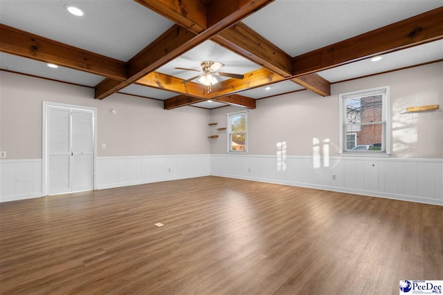 spare room with plenty of natural light, ceiling fan, beamed ceiling, and wood finished floors