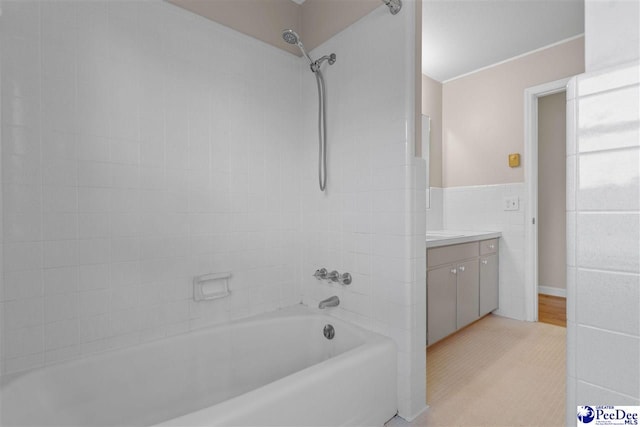 bathroom with tile walls, shower / bath combination, wainscoting, and vanity