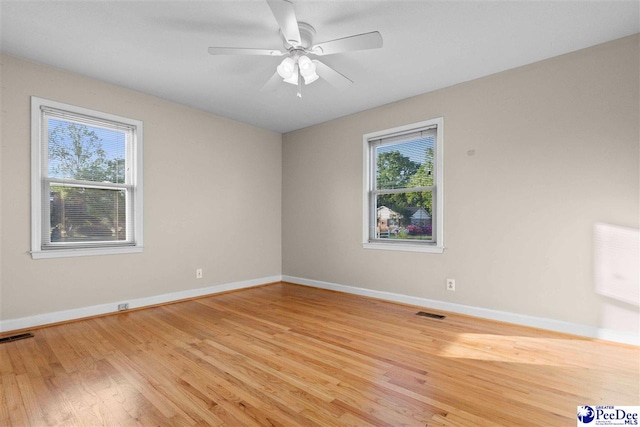 spare room featuring visible vents, baseboards, light wood finished floors, and a ceiling fan