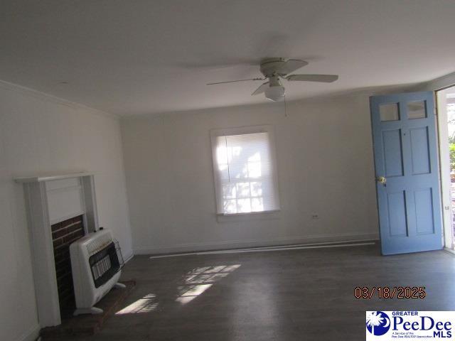 112 N Carolina Ct, Dillon, SC 29536 - unfurnished living room with a fireplace, heating unit, a ceiling fan, baseboards, and wood finished floors
