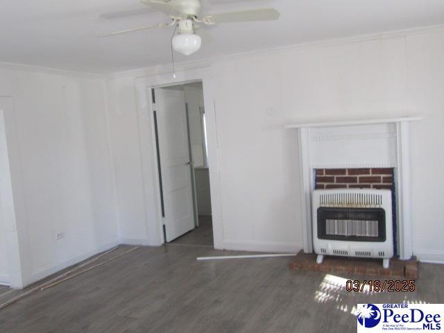 112 N Carolina Ct, Dillon, SC 29536 - unfurnished living room featuring wood finished floors, heating unit, a ceiling fan, and baseboards