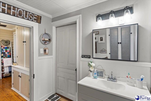 116 Moore St, Bennettsville, SC 29512 - bathroom with a wainscoted wall, ornamental molding, vanity, wood finished floors, and a decorative wall
