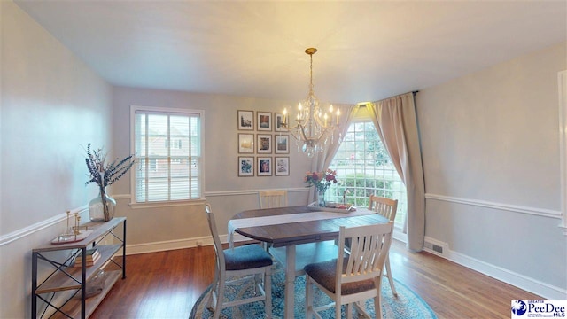 310 S Calhoun Dr, Florence, SC 29501 - dining room with visible vents, an inviting chandelier, plenty of natural light, and wood finished floors
