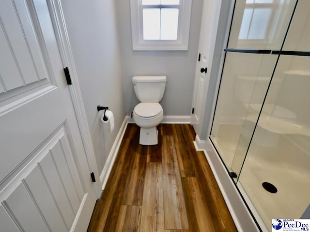 full bath featuring a shower stall, toilet, wood finished floors, and baseboards