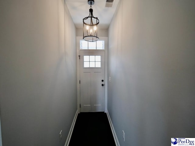 doorway featuring an inviting chandelier, baseboards, and visible vents