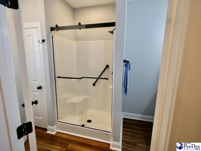 full bath featuring baseboards, wood finished floors, and a shower stall