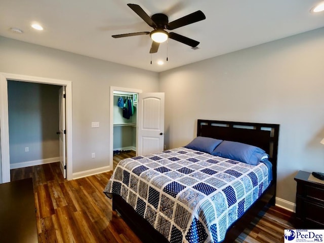 bedroom featuring a spacious closet, recessed lighting, baseboards, and wood finished floors